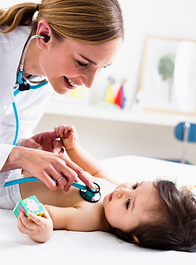 Doctor listening to a baby’s chest with a stethoscope while the infant plays at Mambourin Doctors.